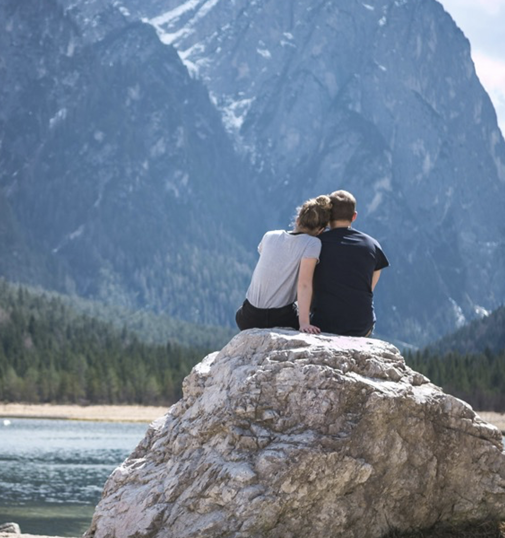 Couple sitting on a rock near a lake